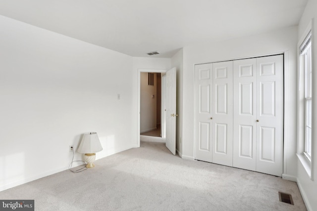 unfurnished bedroom featuring light colored carpet and a closet