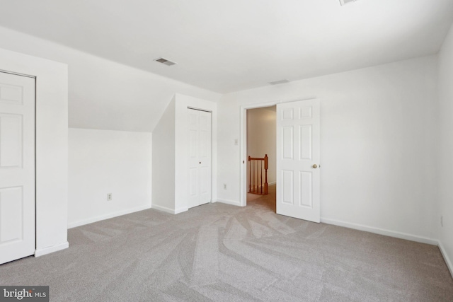 bonus room with lofted ceiling and light carpet