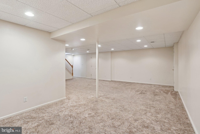 basement featuring light carpet and a drop ceiling