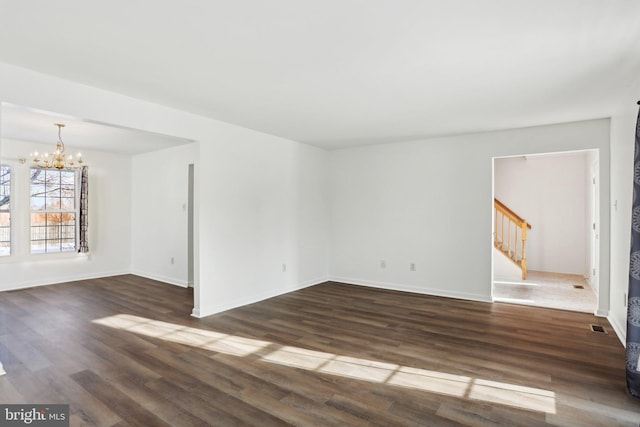 unfurnished room featuring dark hardwood / wood-style flooring and a notable chandelier