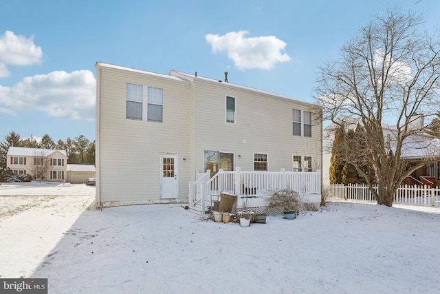 snow covered back of property with a deck