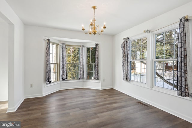 unfurnished dining area with a notable chandelier and dark hardwood / wood-style flooring