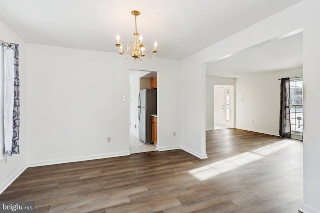 empty room with dark hardwood / wood-style floors and an inviting chandelier