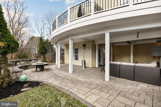 view of patio / terrace with an outdoor living space with a fire pit, ceiling fan, and a balcony