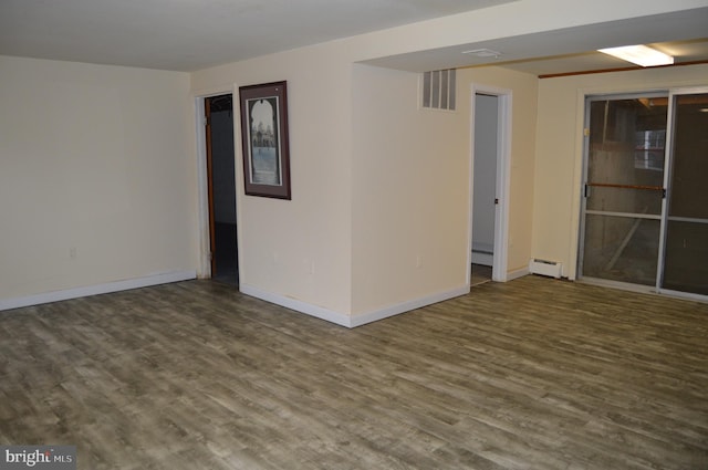 unfurnished room featuring baseboard heating and hardwood / wood-style floors