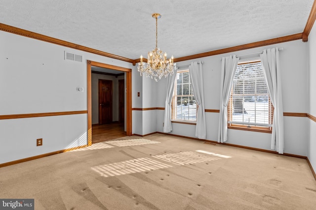 carpeted empty room featuring an inviting chandelier, crown molding, and a textured ceiling