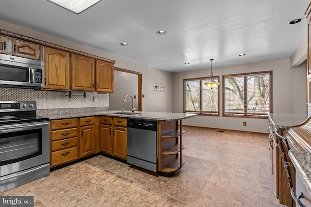 kitchen with appliances with stainless steel finishes, pendant lighting, sink, decorative backsplash, and kitchen peninsula