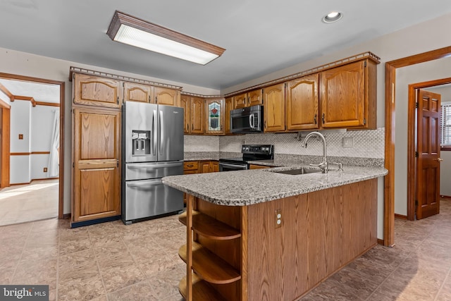 kitchen with sink, tasteful backsplash, appliances with stainless steel finishes, kitchen peninsula, and light stone countertops