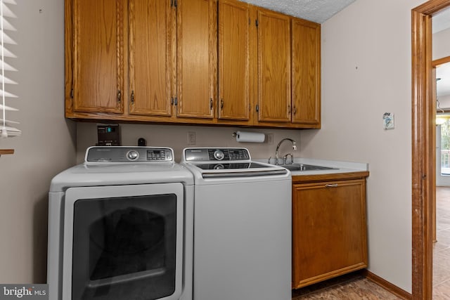 laundry room with cabinets, sink, washing machine and clothes dryer, and a textured ceiling