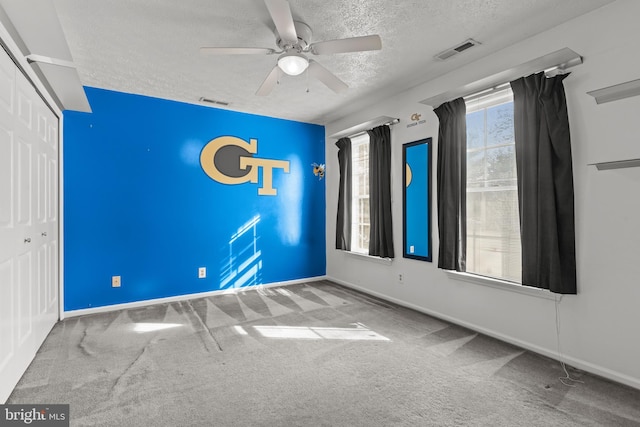 carpeted empty room featuring ceiling fan and a textured ceiling