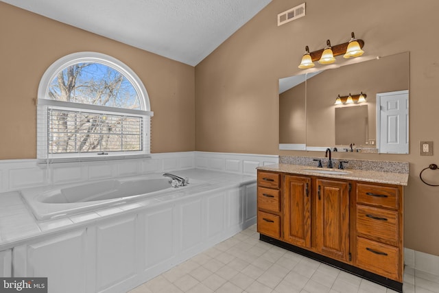 bathroom with lofted ceiling, vanity, a bath, a textured ceiling, and tile patterned floors