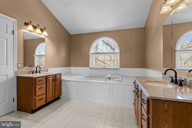 bathroom featuring vanity, a bath, and a textured ceiling