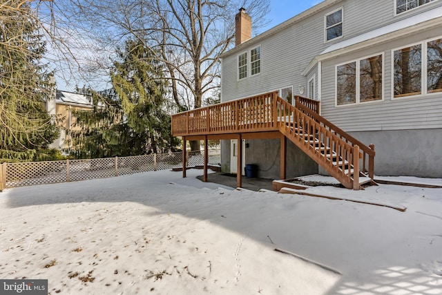 snow covered back of property featuring a wooden deck