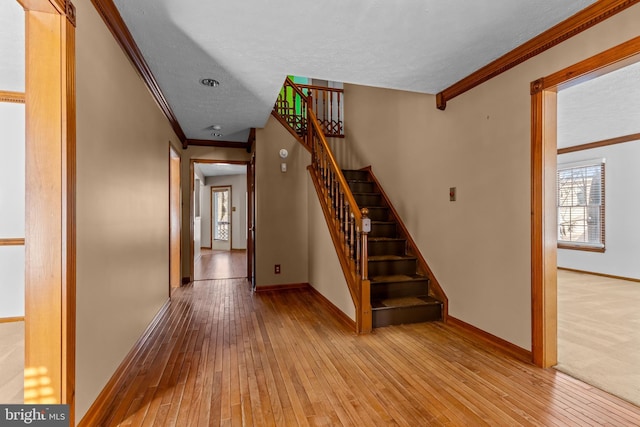 staircase with hardwood / wood-style floors and crown molding