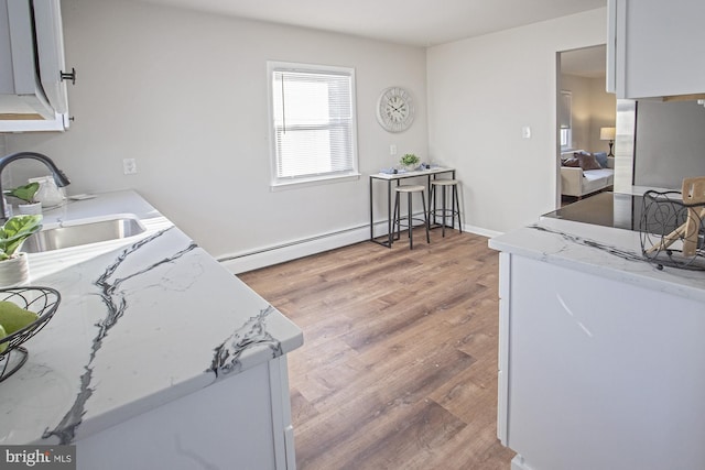 kitchen with a baseboard radiator, light stone countertops, sink, and light wood-type flooring