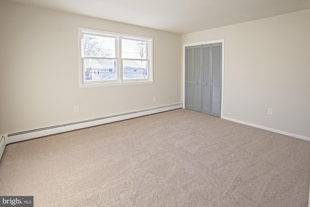 unfurnished bedroom featuring light colored carpet, baseboard heating, and a closet