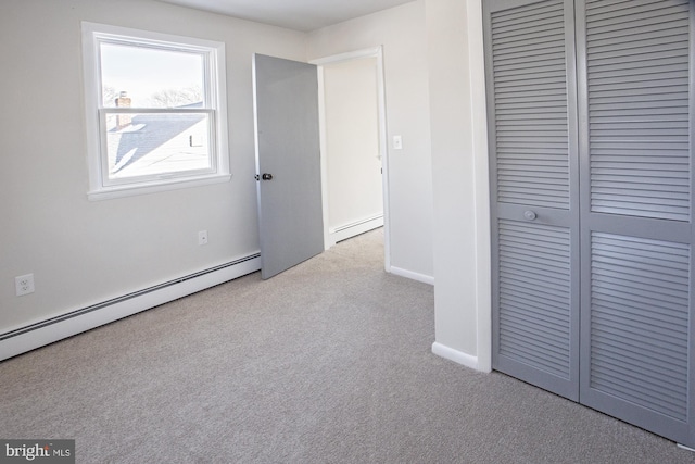 unfurnished bedroom with a baseboard heating unit and light carpet