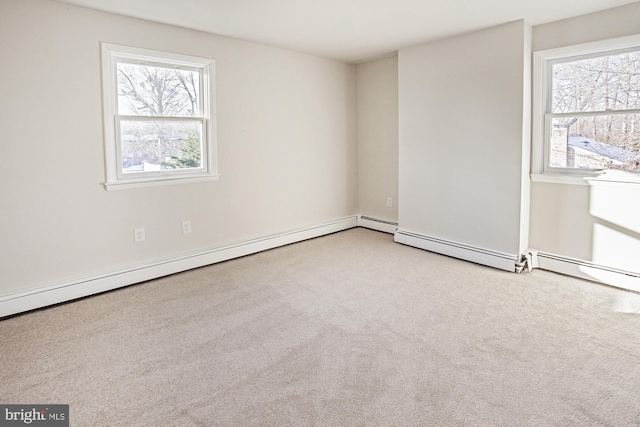 carpeted spare room featuring a baseboard radiator and plenty of natural light