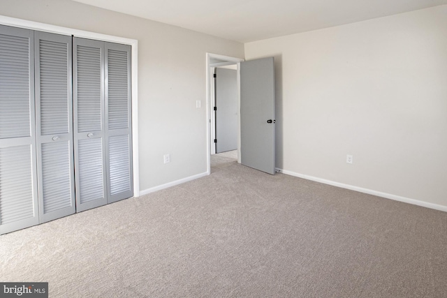 unfurnished bedroom with light colored carpet and a closet