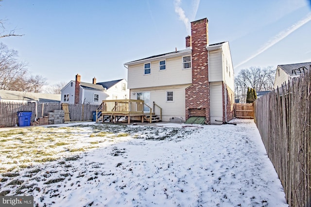 snow covered house with a wooden deck