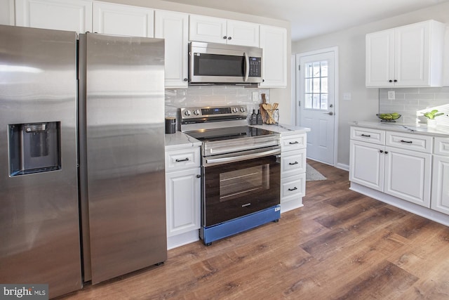 kitchen featuring appliances with stainless steel finishes, white cabinetry, light stone countertops, dark hardwood / wood-style flooring, and decorative backsplash