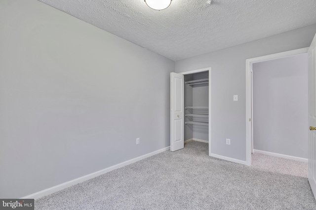 unfurnished bedroom featuring light carpet, a textured ceiling, and a closet