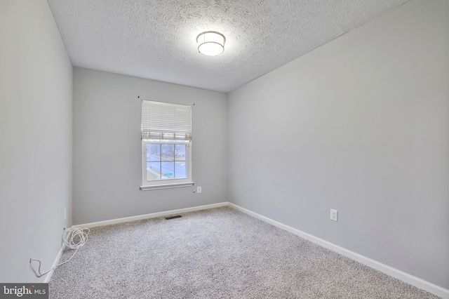 empty room with carpet floors and a textured ceiling