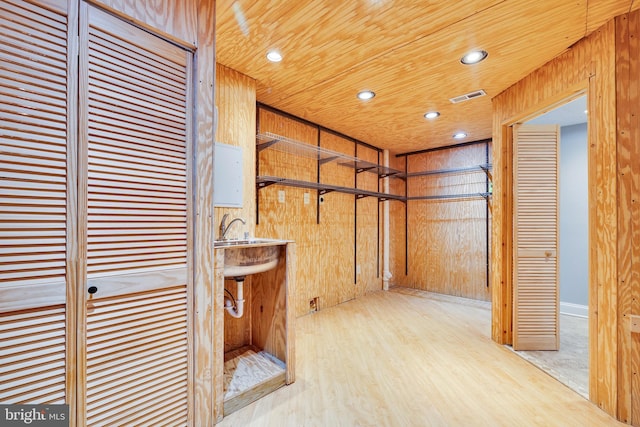 hallway featuring sink, wooden walls, wood ceiling, and light hardwood / wood-style flooring