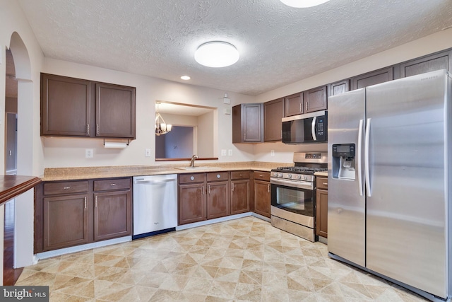 kitchen featuring stainless steel appliances, dark brown cabinets, sink, and a textured ceiling