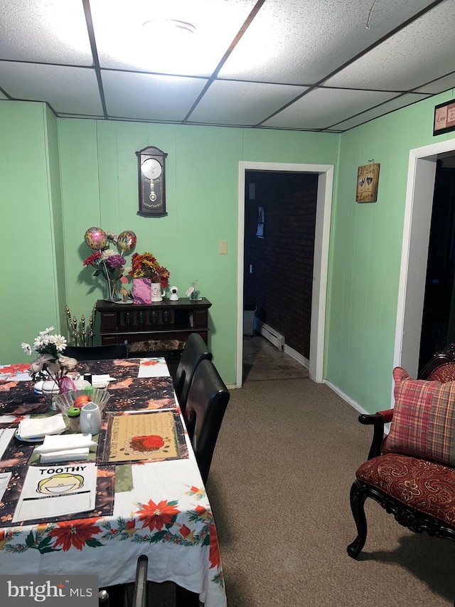 carpeted dining space featuring a baseboard radiator and a drop ceiling