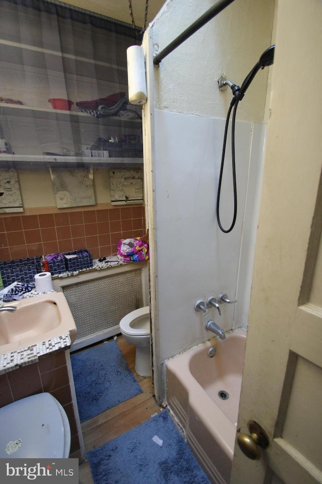 full bathroom featuring toilet, sink, shower / tub combination, hardwood / wood-style floors, and decorative backsplash