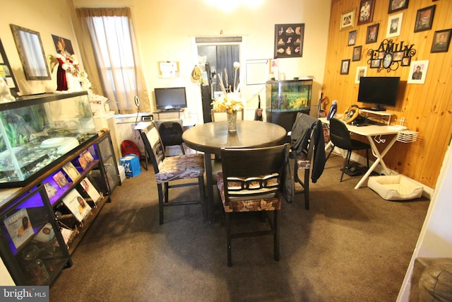 carpeted dining room featuring wooden walls