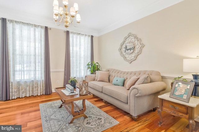 living room featuring a healthy amount of sunlight, wood-type flooring, a chandelier, and ornamental molding