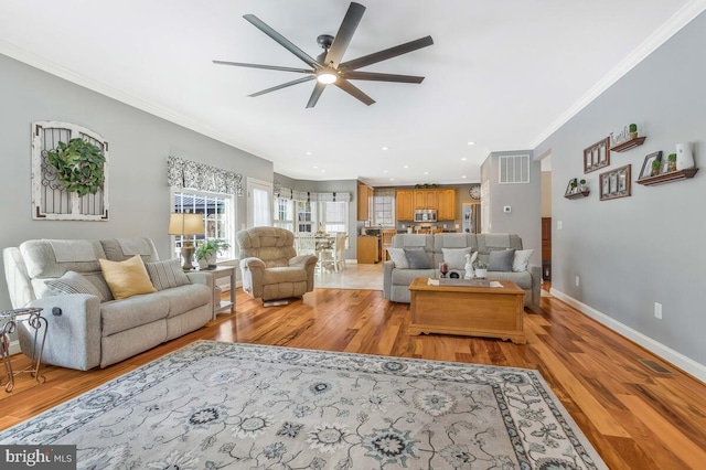 living room with ceiling fan, ornamental molding, and light hardwood / wood-style flooring