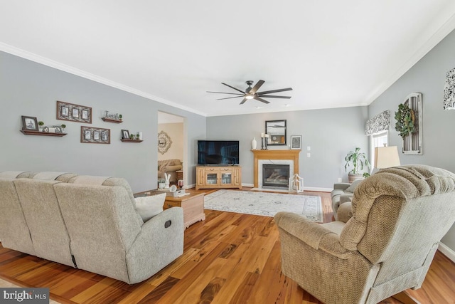 living room with crown molding, ceiling fan, and light wood-type flooring