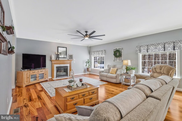 living room with a premium fireplace, crown molding, ceiling fan, and light hardwood / wood-style floors