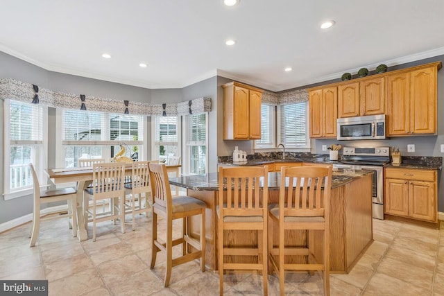 kitchen with a kitchen island, ornamental molding, appliances with stainless steel finishes, and sink