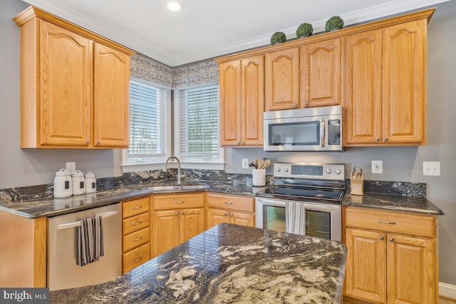 kitchen with stainless steel appliances, sink, and dark stone counters