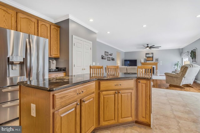 kitchen featuring ornamental molding, a kitchen island, dark stone countertops, and stainless steel fridge