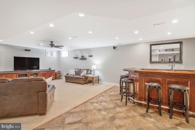 living room with ceiling fan, light colored carpet, and indoor wet bar