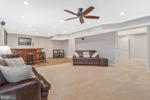 carpeted living room featuring ornamental molding, ceiling fan, and indoor bar