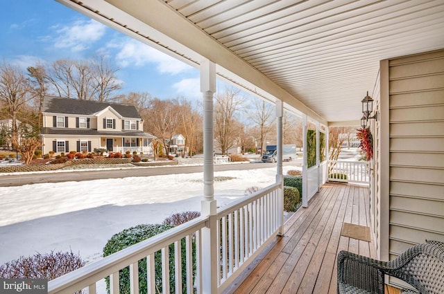 snow covered deck featuring a porch