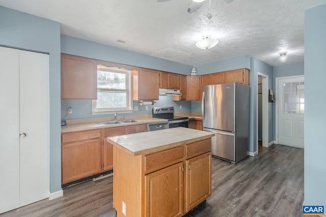 kitchen featuring sink, a textured ceiling, appliances with stainless steel finishes, dark hardwood / wood-style floors, and a kitchen island