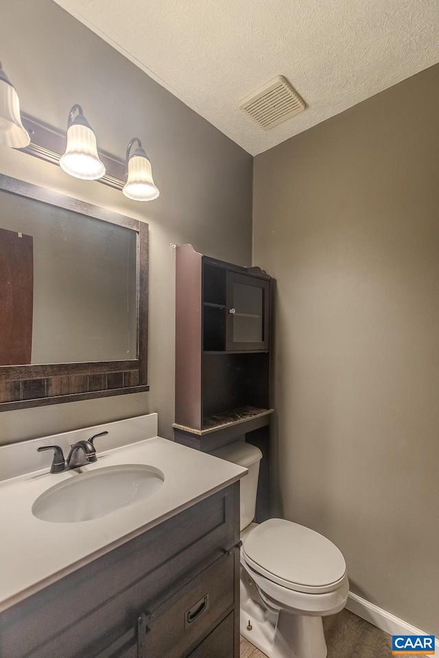 bathroom with vanity, a textured ceiling, and toilet