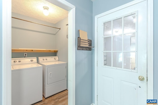 laundry room featuring washing machine and clothes dryer, light hardwood / wood-style floors, and a textured ceiling