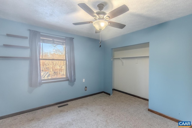 unfurnished bedroom with light carpet, ceiling fan, a closet, and a textured ceiling