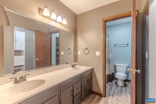 bathroom with toilet, a shower with curtain, wood-type flooring, a textured ceiling, and vanity