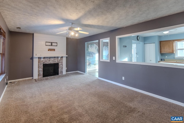 unfurnished living room featuring ceiling fan, light carpet, a textured ceiling, and a fireplace