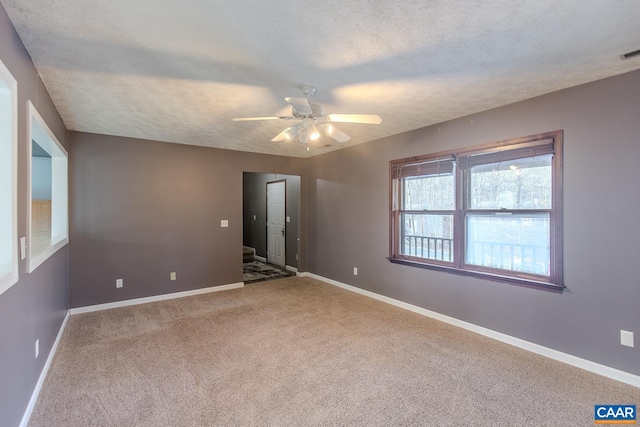 empty room featuring ceiling fan, light colored carpet, and a textured ceiling