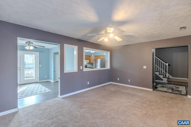 unfurnished living room with ceiling fan, a textured ceiling, and carpet